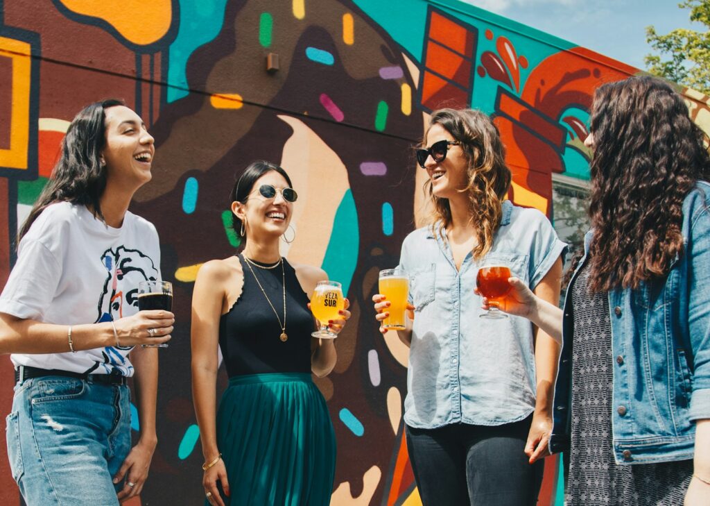 cuatro mujeres sosteniendo bebidas mientras ríen juntas durante el día