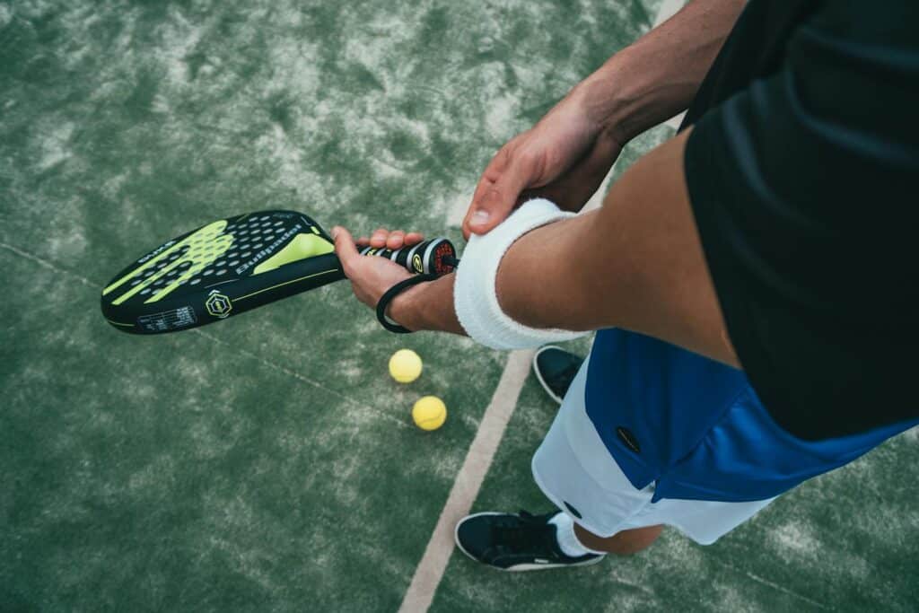 Person hält schwarzen und grünen Tennisschläger