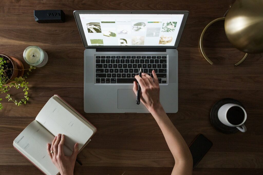 A woman writing a quality fashion blog on a wooden table.