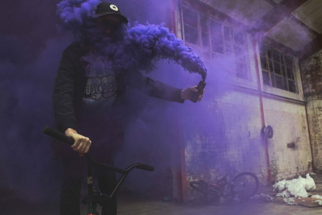 A man riding a bicycle with purple smoke coming out of his mouth, showing a fashionable trend.