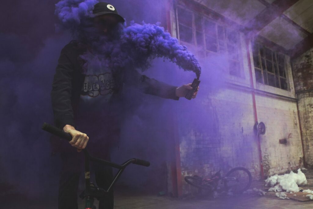 Un hombre en bicicleta con humo morado saliendo de su boca, mostrando una tendencia de moda.