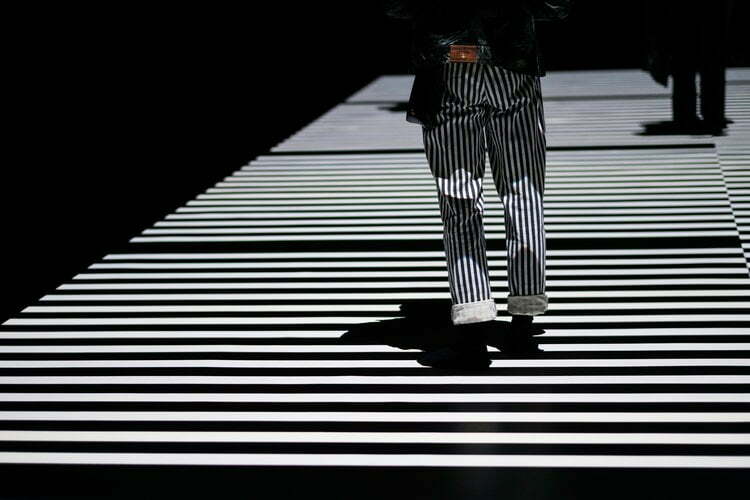 A man walking on a catwalk with striped lines.