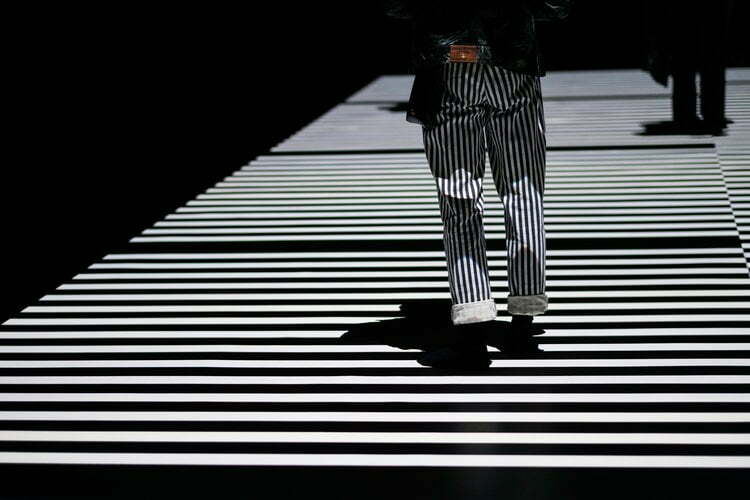 Un homme marchant sur une passerelle aux lignes rayées.