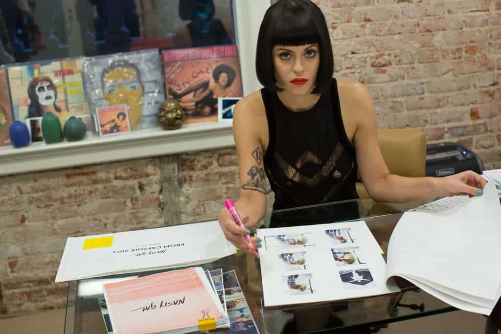 A woman creating her own fashion start-up surrounded by papers and books.