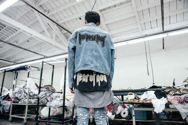 A man wearing a denim jacket in a factory, representing the menswear brand.