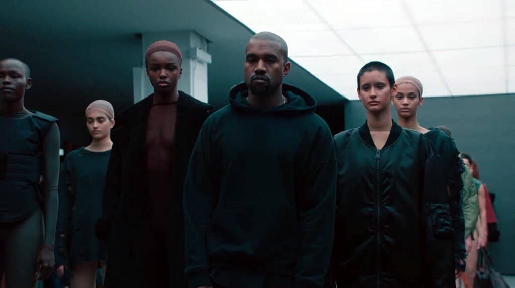 A group of people standing in a corridor discuss their new menswear brand.