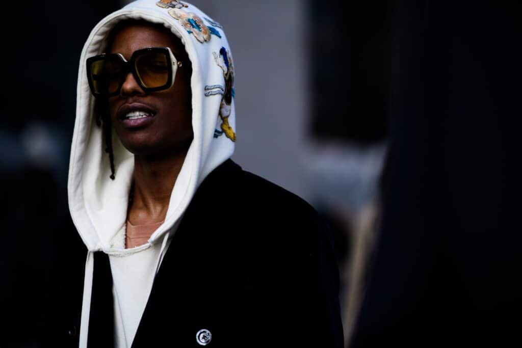 Un homme portant un sweat à capuche élégant et des lunettes de soleil en marchant dans la rue.