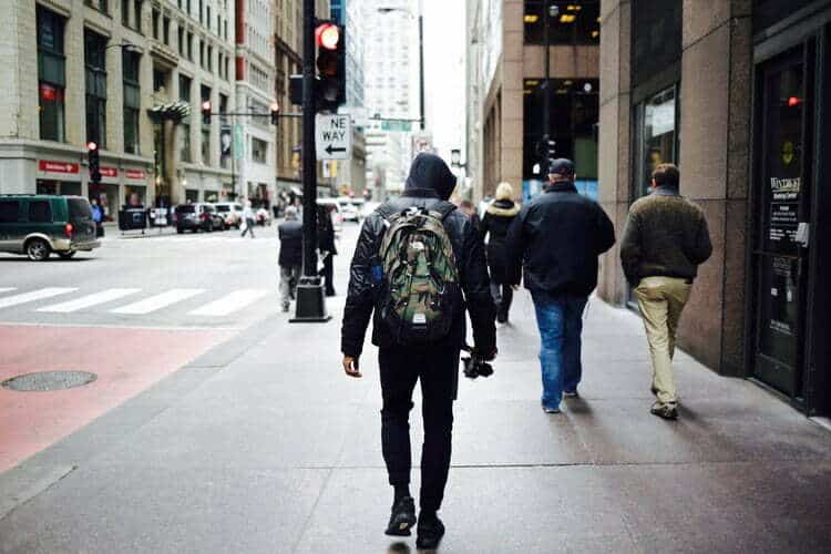 Ein Mann, der mit einem Rucksack eine Straße in der Stadt entlanggeht und über Trendprognosen nachdenkt.