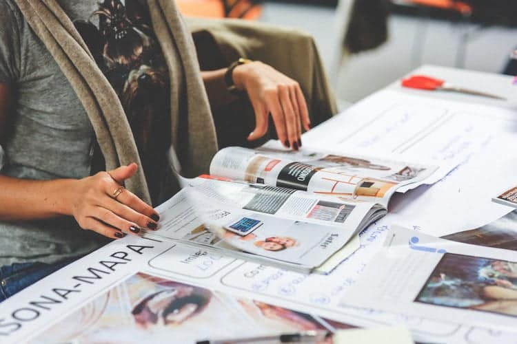 Una mujer está sentada en una mesa con revistas normcore.