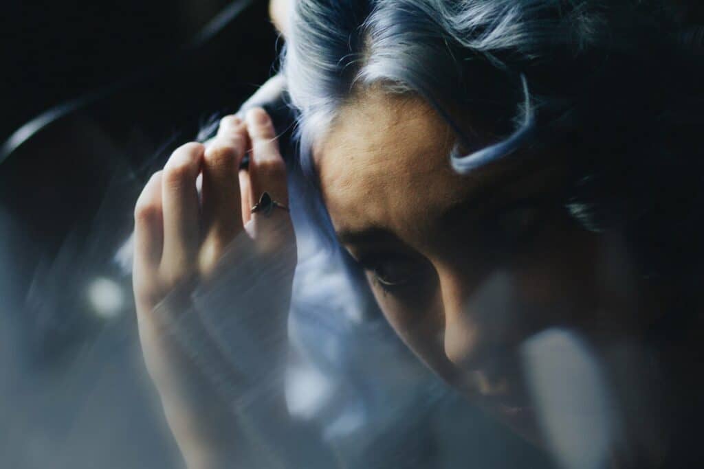 Une femme aux cheveux bleus excentriques et à la bague frappante montre les tendances futuristes, offrant un aperçu des coulisses des prévisions de mode.