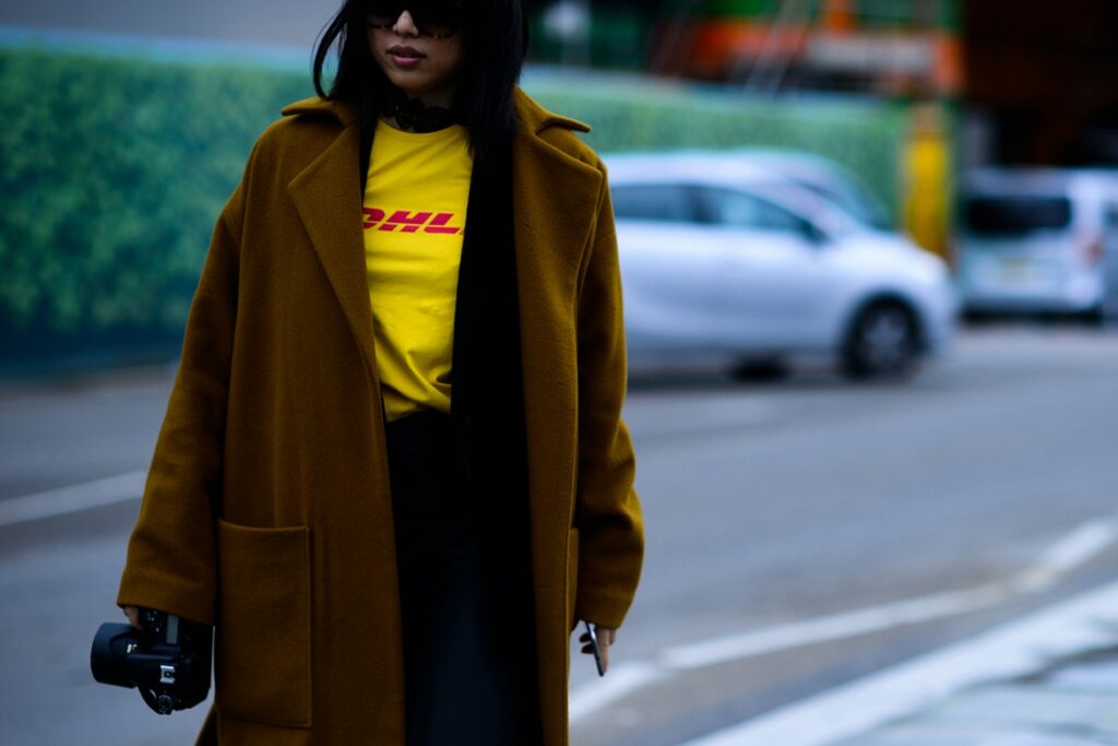 Eine Frau in einem gelben Mantel geht die Straße entlang.