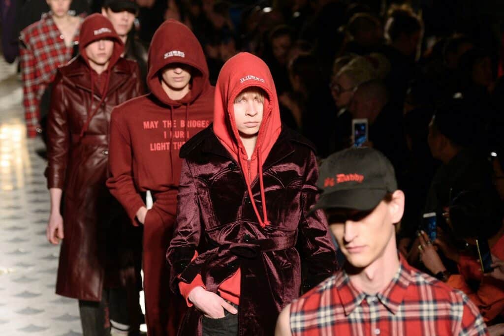 Hombres caminando por una pasarela con sudaderas rojas.