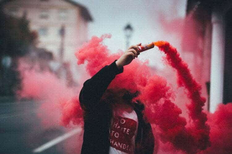 A person displaying a red smoke in the street with a 'hip hop' twist upset by 'pop'.