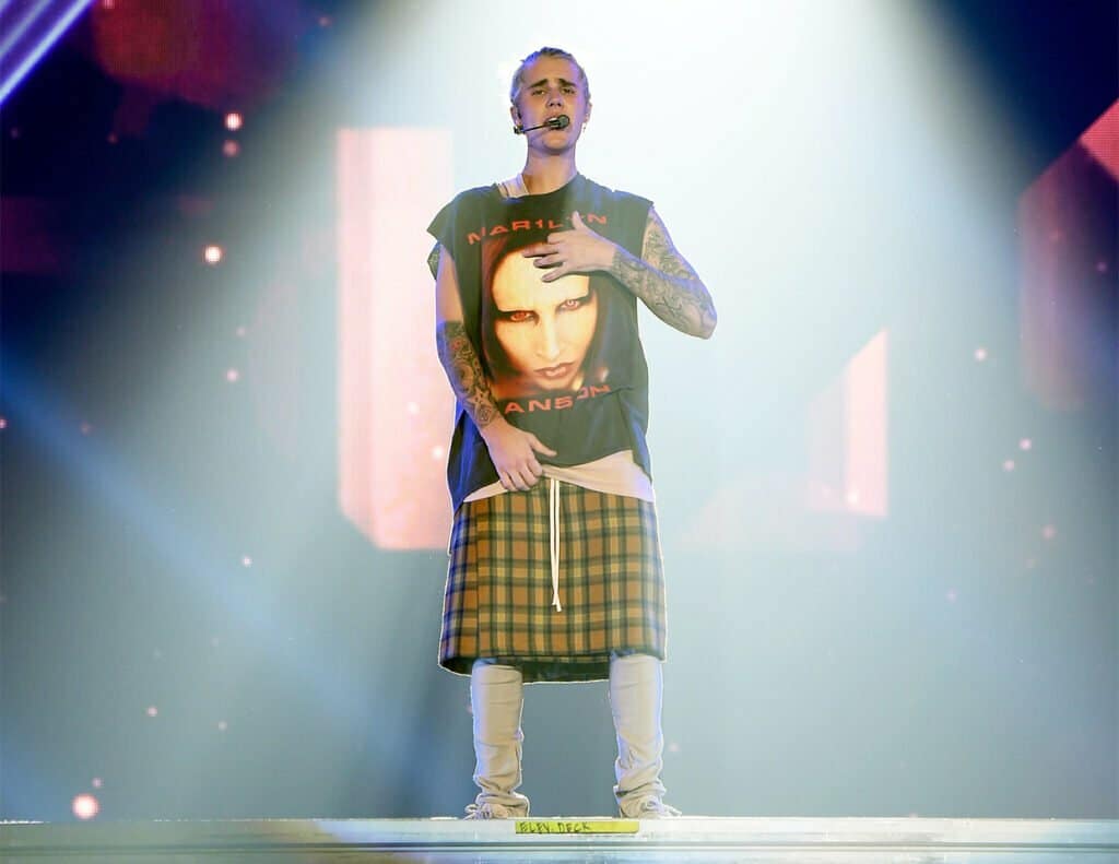 Justin Bieber performs on stage in a kilt, combining hip hop and pop influences.