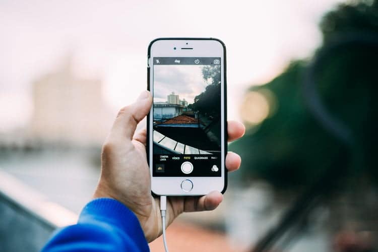 Person, iPhone, die ein Foto macht: Eine Person benutzt ein iPhone, um eine Stadtlandschaft zu fotografieren.