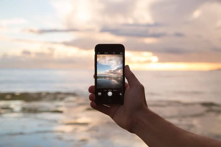 スマートフォンで海を撮影する人。