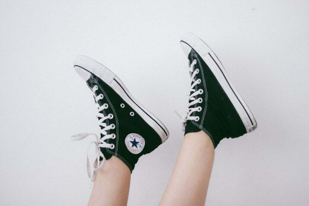 A woman wearing green trainers on a white wall.Key words: fashion brand, coronavirus.