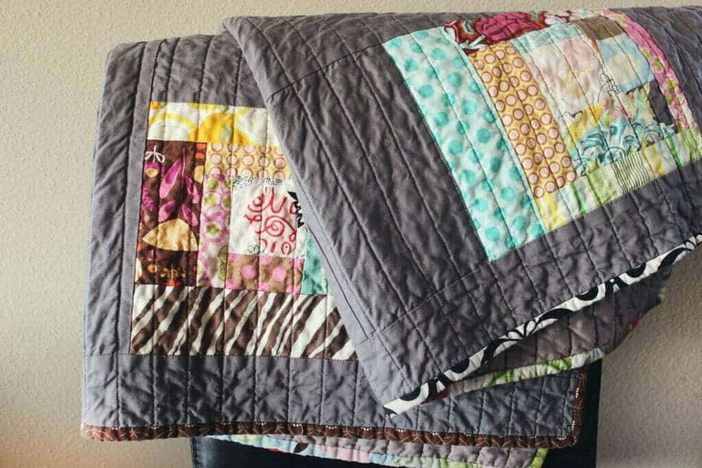 Two patchwork quilts are stacked on top of a chair.