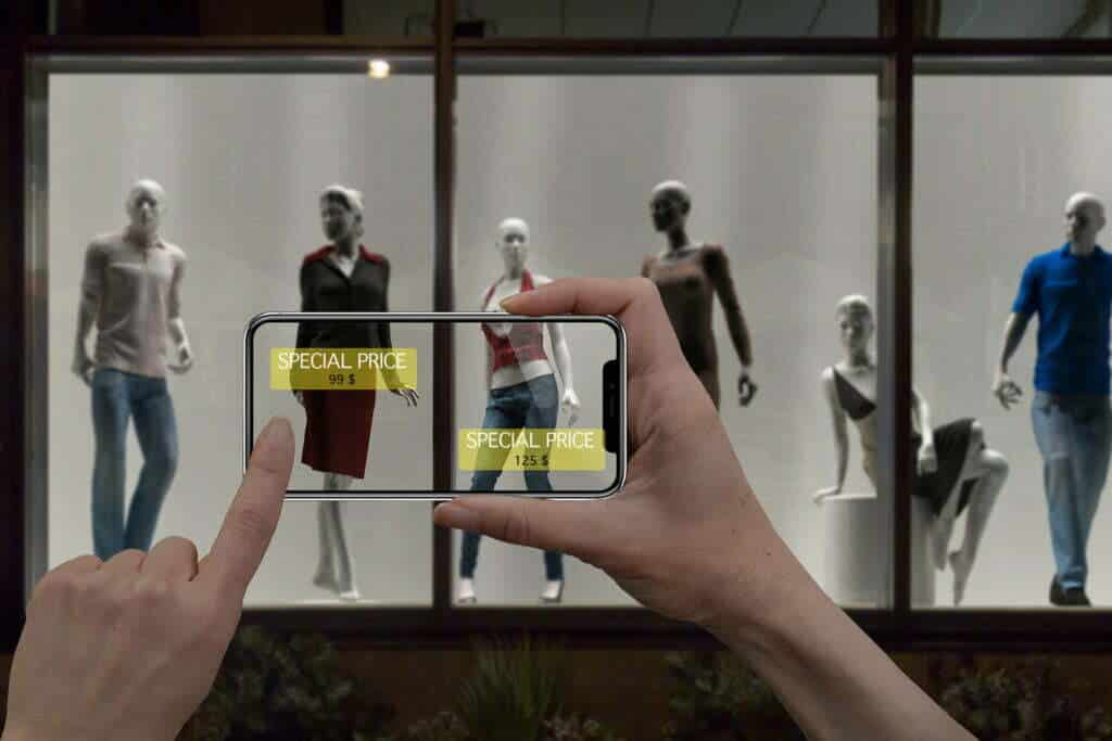 A person capturing the changes in fashion design during a COVID year by photographing mannequins in a shop window.