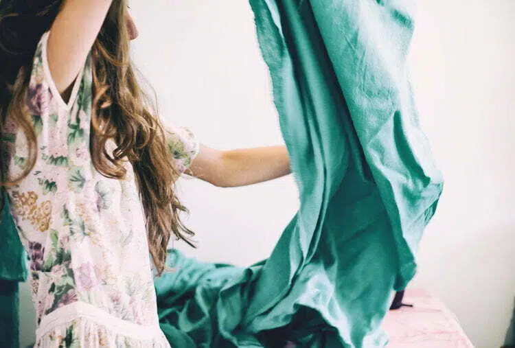 Una ragazza sta tenendo un panno verde per un moodboard su un letto.
