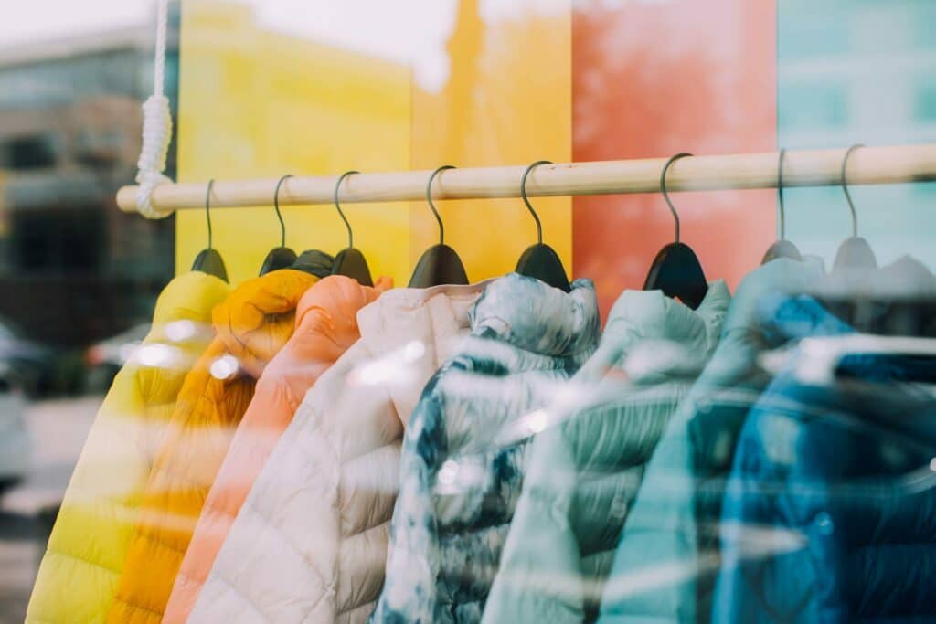 Bunte Jacken von neuen Designern hingen auf einem Gestell vor einem Schaufenster.