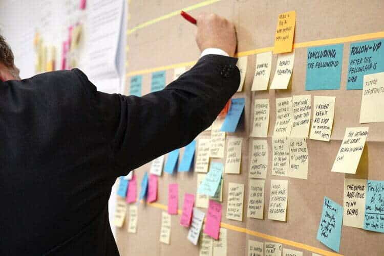 Un uomo che utilizza i post-it per scrivere e fare brainstorming di idee per incentivi aziendali in Italia.