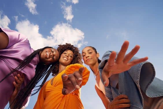 A group of fashionable women pose in front of a blue sky, displaying iconic fashion items and capturing the market trends of 2023.