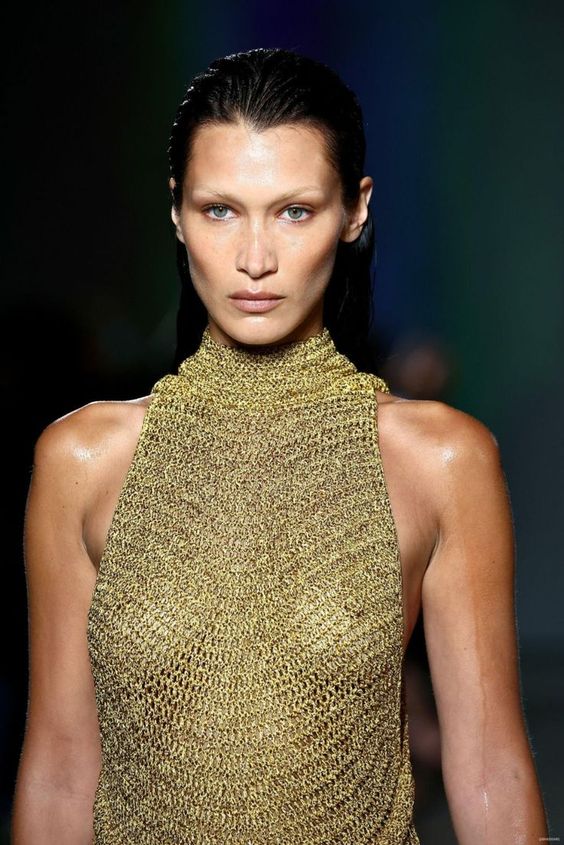 模特在 T 台上展示的金色上衣，突出了标志性时尚单品和市场趋势。