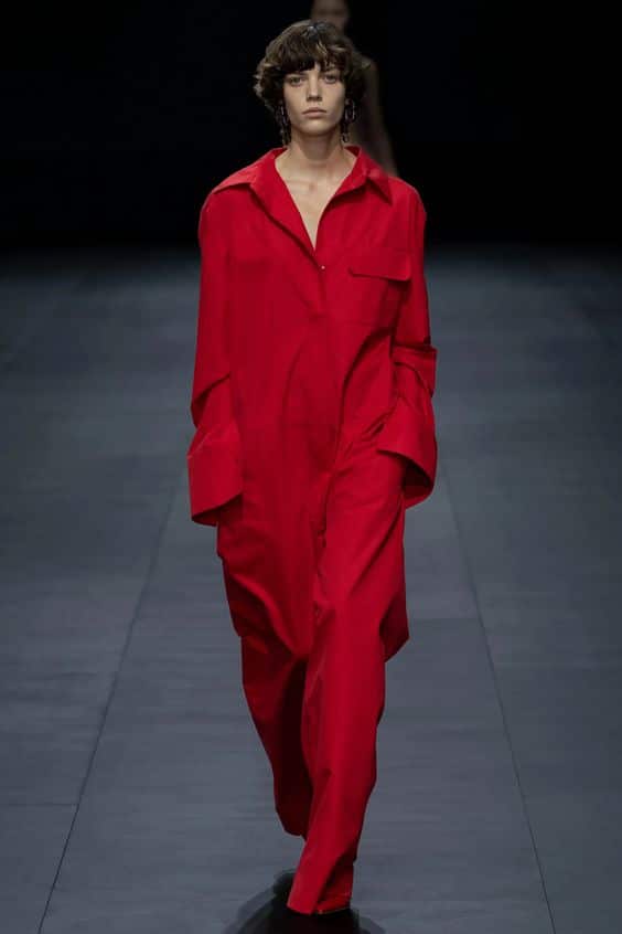 Una modella di Vogue esibisce una tuta rossa in passerella, mostrando le ultime tendenze della moda per il 2023.