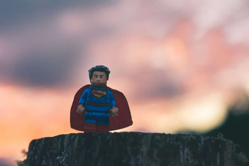 Un Superman de Lego de pie sobre un tronco al atardecer, blog de moda.