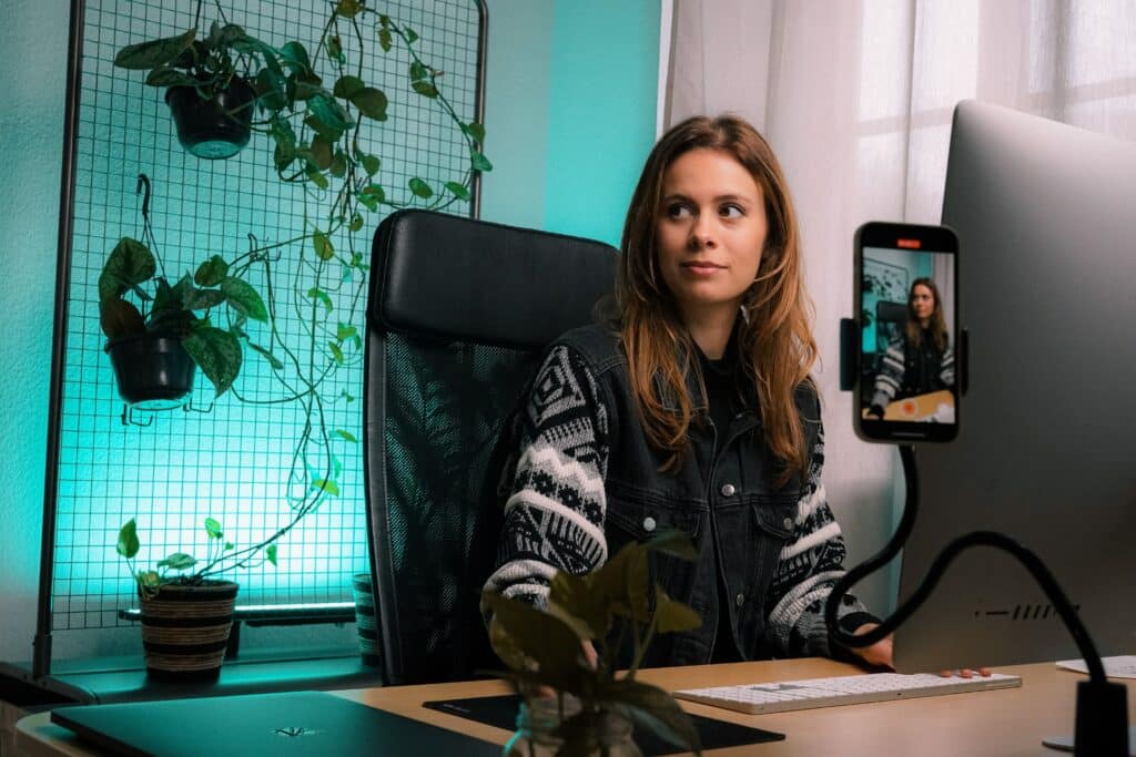 A woman in front of a computer with a plant.