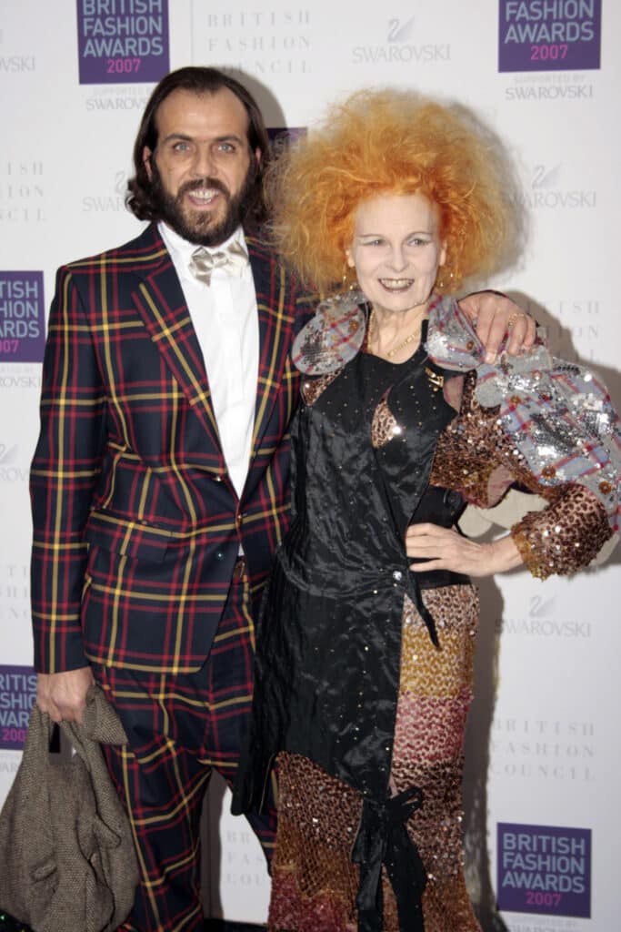 A fashionable man and woman standing next to each other on a red carpet.