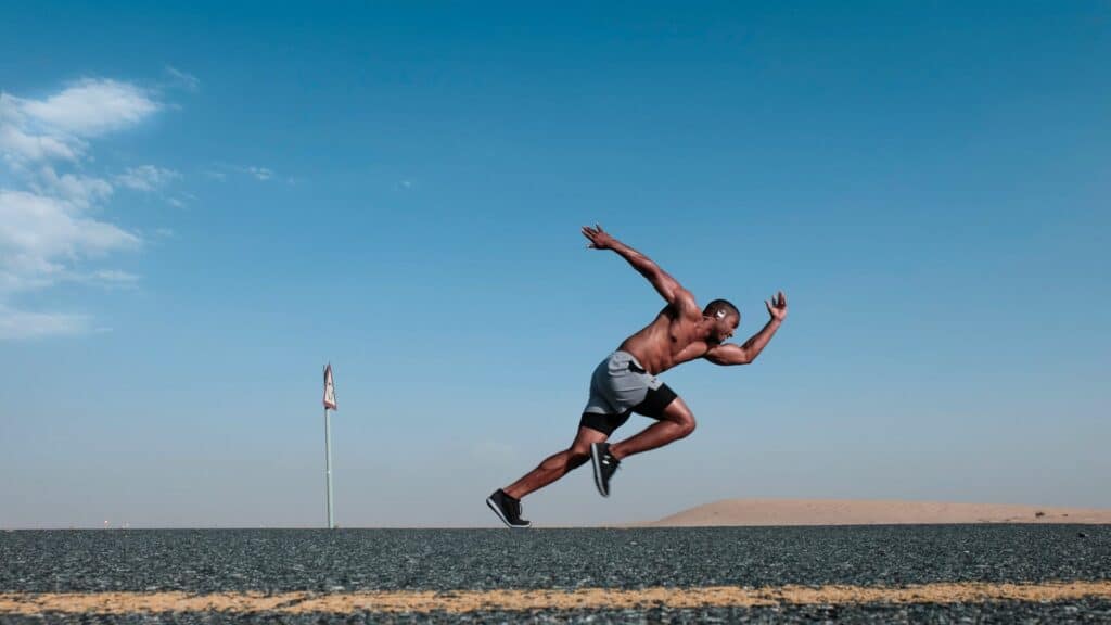 A man wearing sportswear jumps into the air on a deserted road.