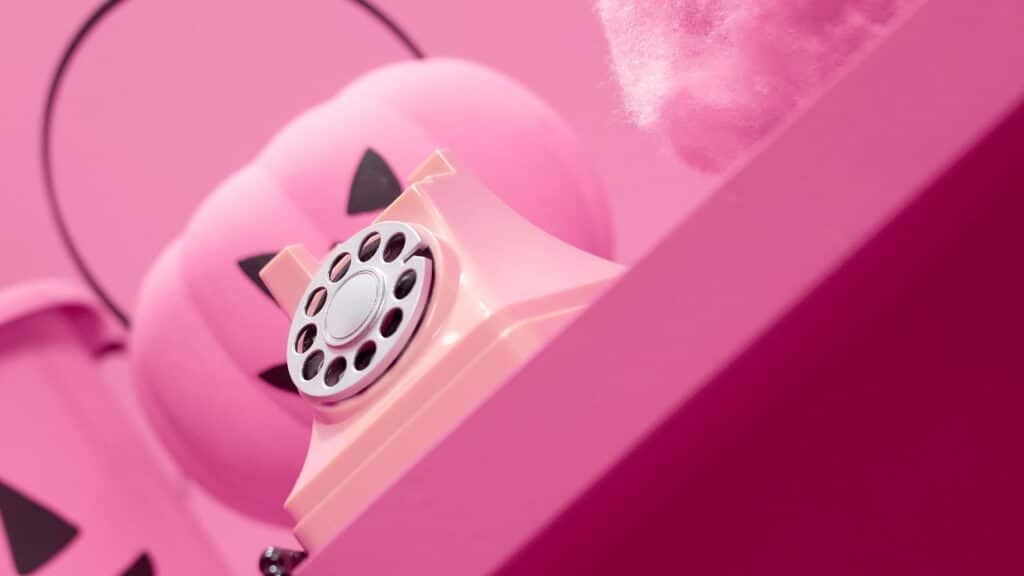 Un teléfono rosa con temática Barbie colocado en una pared a juego.