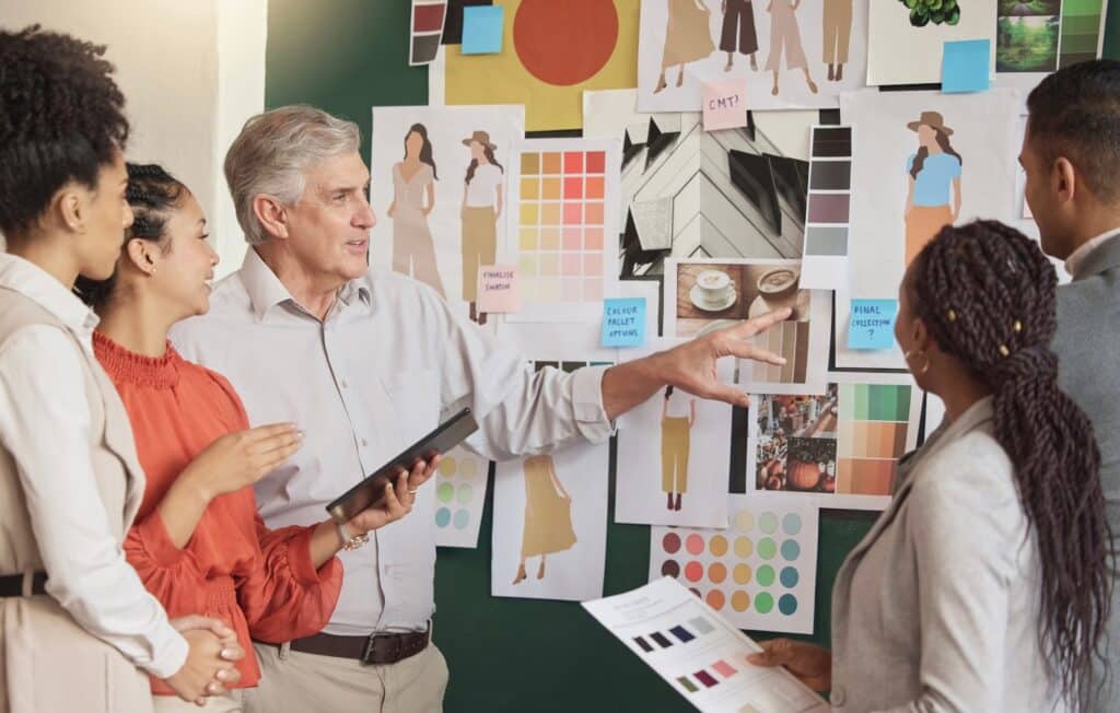 Un groupe de designers, tous âgés de plus de 40 ans, autour d'un tableau noir.