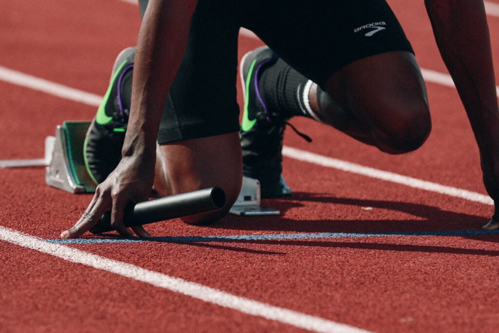 Une personne personne en tenue de sport s'accroupit sur une piste.