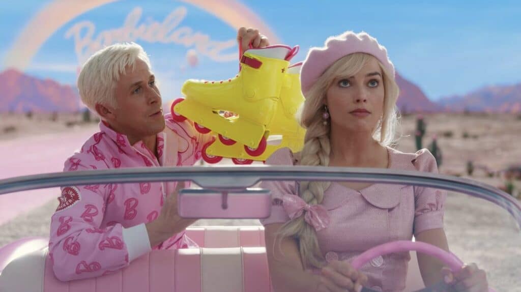 A man and a woman dressed in pink, reminiscent of Barbie dolls, are seen in a car.