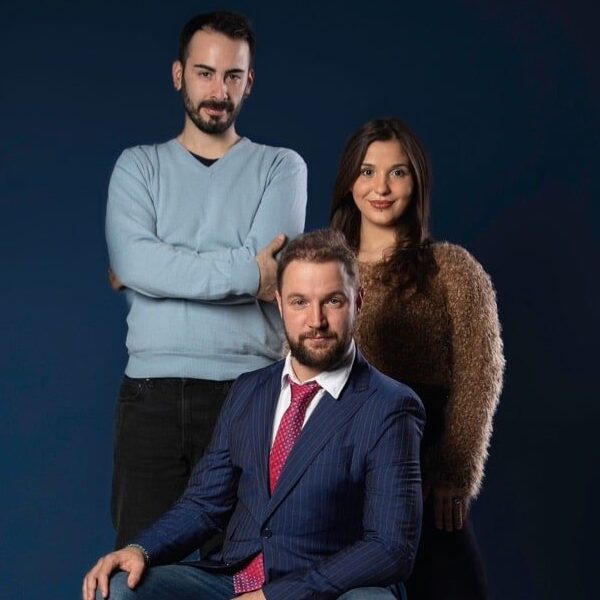 Three people posing for a photo in front of a blue background.