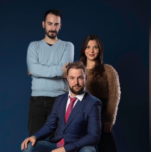 Three people posing for a photo in front of a blue background.