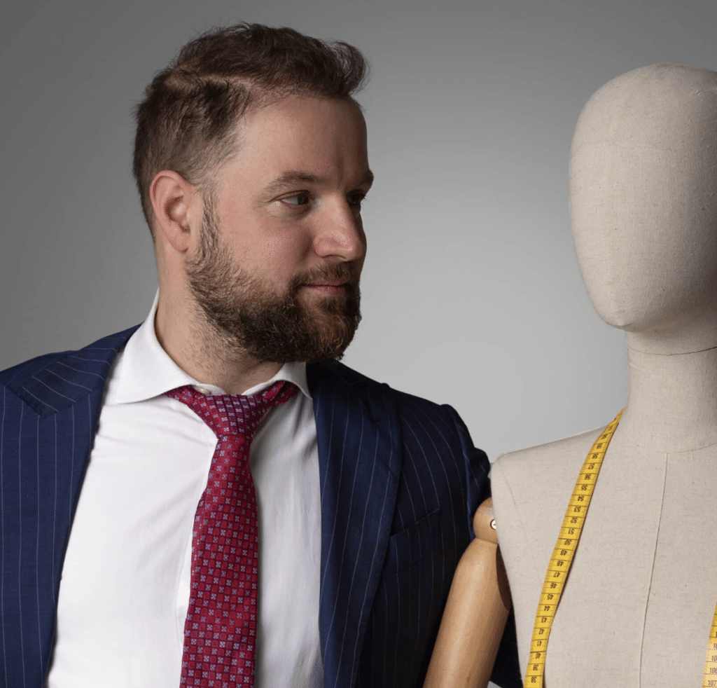 A man in a suit standing next to a mannequin for a fashion blog.