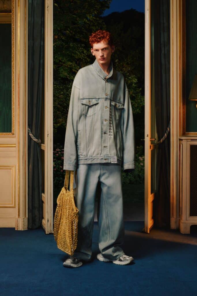 A dapper man in a denim jacket flaunts the latest fashion trends while confidently holding a wicker basket.