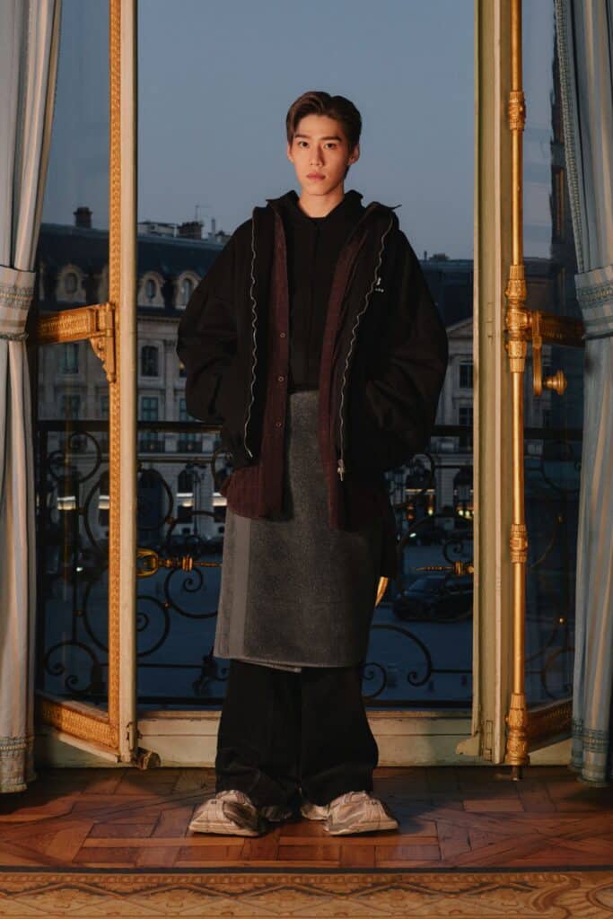 一位优雅的年轻人站在橱窗前，展示 2024 年的最新时尚潮流。