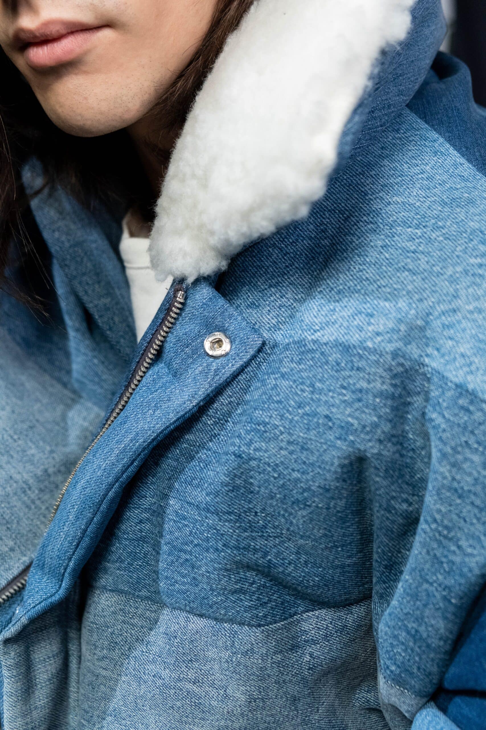 Un uomo alla moda con una giacca blu ornata da un collo di pelliccia, che mostra le tendenze della moda 2024.