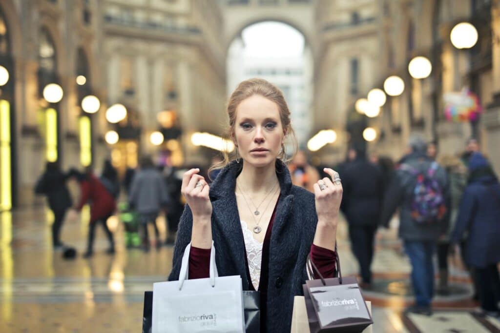 Woman Wearing Black Coat Holding Assorted-color Shopping Bags on Building