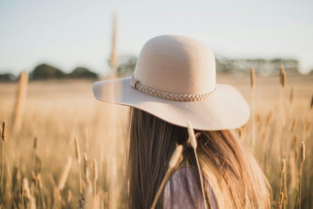 woman wearing beige sun hat standing on wheat field